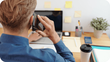 Person with phone in front of a laptop